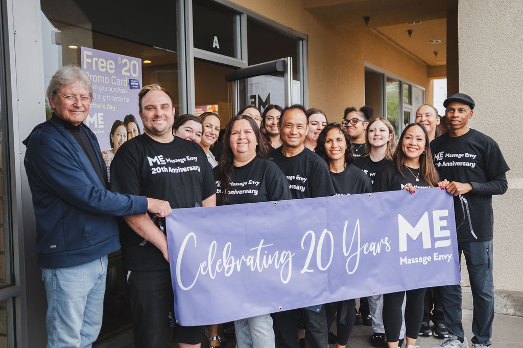 Massage Envy team holding a Celebrating 20 Years banner